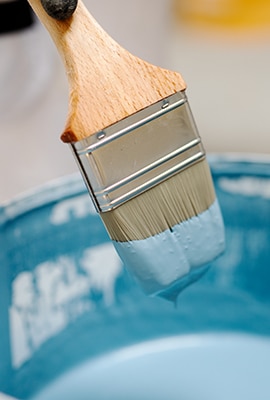 Malerpensel med maling, over malerspand